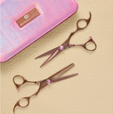 two pink salon scissors with pink gem accents are arranged on a textured beige surface next to a pink iridescent pouch with a Olivia Garden logo.